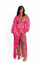 Woman wearing a pink paisley dress with a white background